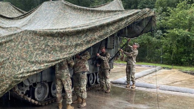 Soldiers in uniform setting up Vehicle-Integrated Camouflage System
