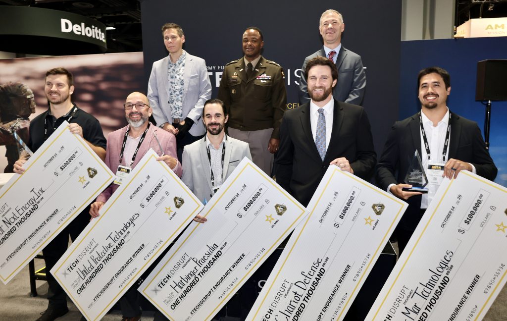 Winners of xTech|Disrupt Endurance pose with Army Acquisition Executive HON Brent Ingraham, PIT Director COL Daiyaan, and FUZE Director Dr. Matt Willis at AUSA 2026.