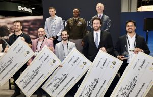 Winners of xTech|Disrupt Endurance pose with Army Acquisition Executive HON Brent Ingraham, PIT Director COL Daiyaan, and FUZE Director Dr. Matt Willis at AUSA 2026.